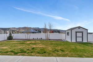 View of yard featuring a mountain view, a fenced backyard, a shed, and an outdoor structure