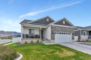 Craftsman-style home featuring covered porch, a mountain view, a front lawn, concrete driveway, and an attached garage