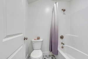 Full bath with toilet, shower / bath combo, tile patterned floors, and baseboards
