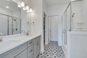 Full bath featuring double vanity, a shower stall, tile patterned floors, and a sink