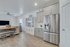 Kitchen featuring light wood-style flooring, ceiling fan, light countertops, baseboards, and stainless steel fridge with ice dispenser