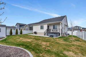 Rear view of house featuring a fenced backyard, a yard, a hot tub, a residential view, and a patio area