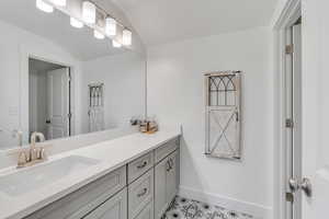 Bathroom featuring tile patterned floors, vanity, vaulted ceiling, and baseboards