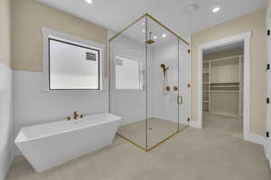 Full bathroom with a soaking tub, recessed lighting, a shower stall, and a spacious closet
