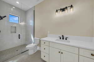 Bathroom featuring tile patterned floors, a shower stall, toilet, and vanity