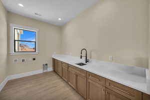 Washroom featuring hookup for an electric dryer, a sink, light wood-style floors, washer hookup, and visible vents