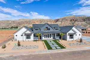 View of front of house with a standing seam roof, metal roof, a front yard, a mountain view, and french doors
