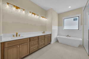 Full bathroom with double vanity, a sink, and a soaking tub