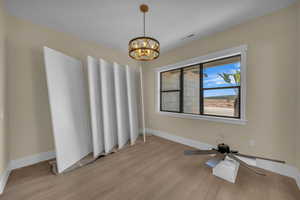 Spare room featuring baseboards, visible vents, a notable chandelier, and light wood-style floors