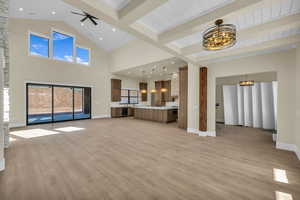 Unfurnished living room with beam ceiling, a chandelier, light wood finished floors, and baseboards
