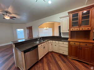Kitchen with dark wood finished floors, a sink, stainless steel dishwasher, arched walkways, and ceiling fan with notable chandelier