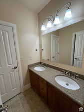 Bathroom with tile patterned flooring, a sink, double vanity, and baseboards