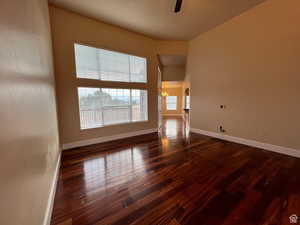 Spare room with dark wood-style flooring, baseboards, and ceiling fan with notable chandelier