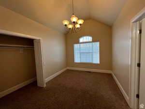 Unfurnished bedroom with a chandelier, baseboards, carpet, and vaulted ceiling
