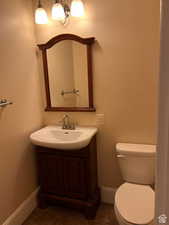 Bathroom featuring toilet, tile patterned flooring, vanity, and baseboards