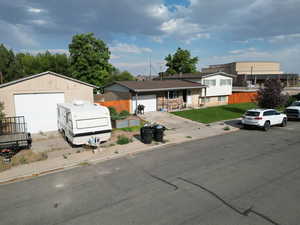 Tri-level home featuring a detached garage, fence, and a front lawn