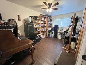 Home office featuring ceiling fan and dark wood-style flooring