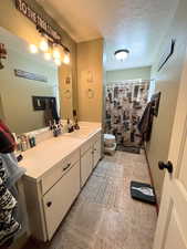 Bathroom with curtained shower, toilet, a textured ceiling, and vanity