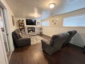 Living area with a fireplace, a textured ceiling, visible vents, and dark wood-style floors