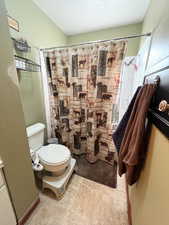 Bathroom featuring toilet and a shower with curtain