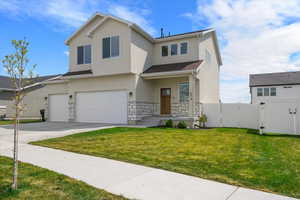 View of front of home with fence, stone siding, a gate, an attached garage, and stucco siding
