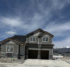 Craftsman-style home with board and batten siding, stone siding, a mountain view, concrete driveway, and an attached garage