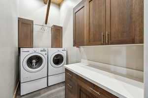 Laundry area with separate washer and dryer, cabinet space, and light wood finished floors