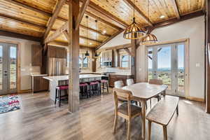 Dining area featuring french doors, lofted ceiling with beams, light wood-type flooring, and wooden ceiling