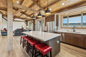 Kitchen featuring a sink, open floor plan, stainless steel appliances, and wooden ceiling
