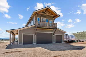 View of front of home with dirt driveway and a balcony