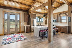 Kitchen with a sink, wooden ceiling, stainless steel appliances, a breakfast bar area, and light countertops