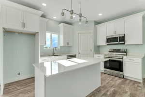 Kitchen featuring appliances with stainless steel finishes, a kitchen island, light wood finished floors, and a sink