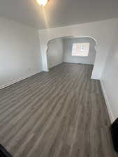 Additional living space featuring arched walkways, dark wood-style flooring, and baseboards. 983 29th St.