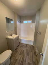 Full bathroom featuring wood finished floors, toilet, vanity, a textured ceiling, and bathtub / shower combination. 2903 Jackson