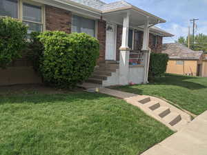 Property entrance with brick siding, a yard, and roof with shingles