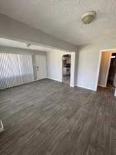 Unfurnished room featuring dark wood finished floors, visible vents, arched walkways, baseboards, and a textured ceiling.2903 Jackson