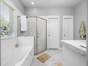 Bathroom with baseboards, recessed lighting, a stall shower, and a garden tub