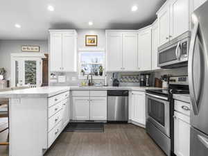 Kitchen with stainless steel appliances, a healthy amount of sunlight, a peninsula, and a sink
