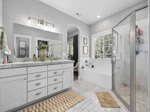 Bathroom featuring a double sinks, a stall shower, double vanity, and a bath