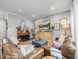 Living area featuring recessed lighting, arched walkways, crown molding, and baseboards