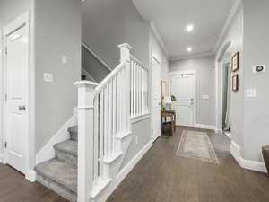 Foyer featuring wood finished floors, arched walkways, stairs, ornamental molding, and baseboards