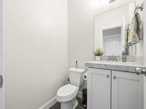 Half bathroom featuring toilet, vanity, and baseboards