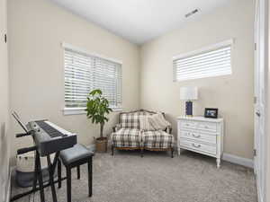 Living area featuring carpet flooring, visible vents, and baseboards