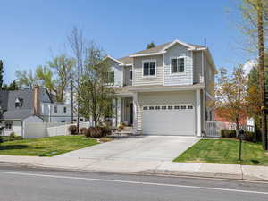 Traditional-style home featuring fence, a front yard, concrete driveway, and an attached garage