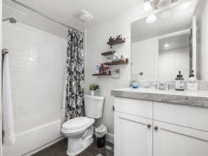 Full bathroom featuring baseboards, shower / bath combo with shower curtain, toilet, wood finished floors, and vanity