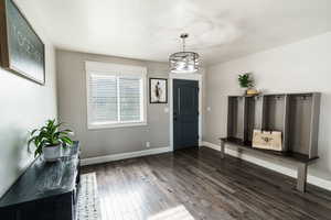 Entryway featuring dark wood-style floors, baseboards, visible vents, and a chandelier