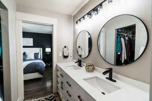 Bathroom featuring wood finished floors, ensuite bath, double vanity, and a sink