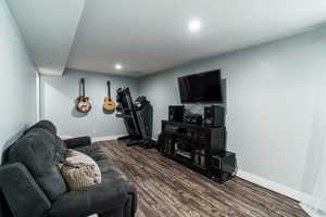 Living room with dark wood finished floors, baseboards, a textured ceiling, and recessed lighting