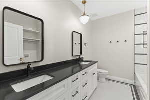Full bath featuring toilet, tile patterned flooring, a sink, and double vanity