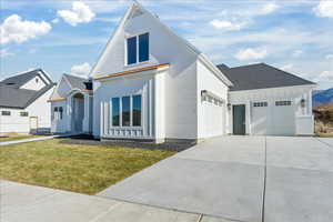 View of front of house featuring brick siding, driveway, board and batten siding, and a front yard